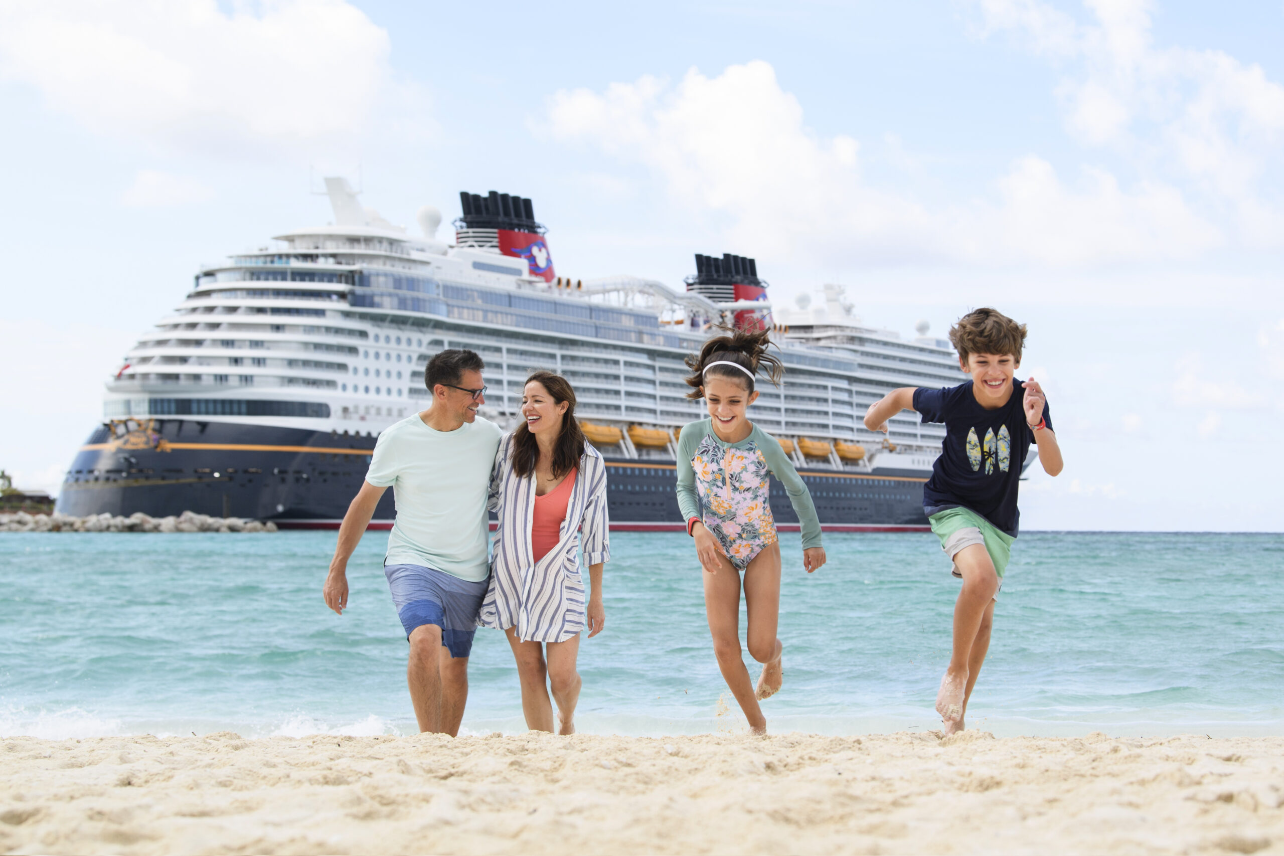Family of four on the beach at Castaway Cay in front of Disney Cruise ship